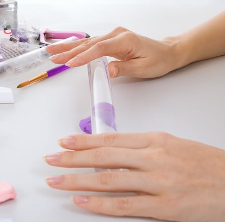 Woman rolling purple clay with acrylic rolling pin.