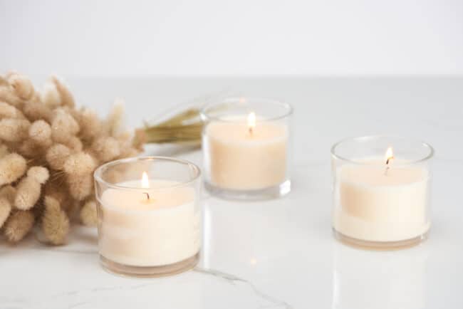 3 white candles in glass containers.