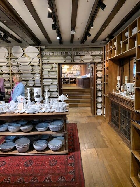 Wooden panelled room with selection of crockery displayed on cabinets and tables in Liberty's of London.