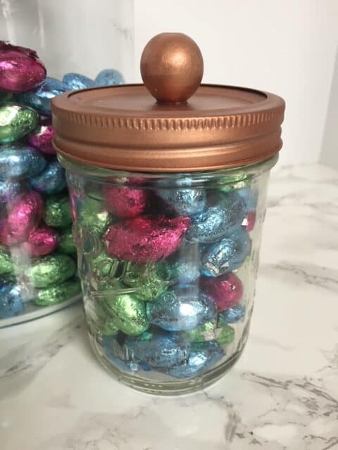 Copper top glass storage jar filled with chocolate easter eggs.