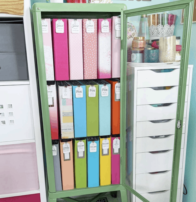 Green glass door cabinet full of colored binders.