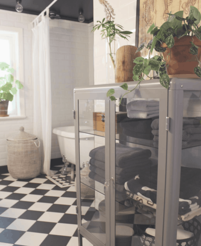 White glass cabinet full of towels in a bathroom.