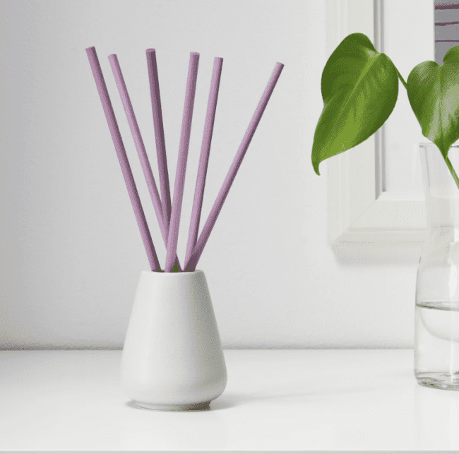White vase with 6 pink scented sticks.