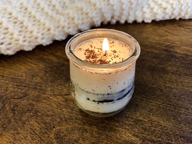 Lit candle on wooden table.