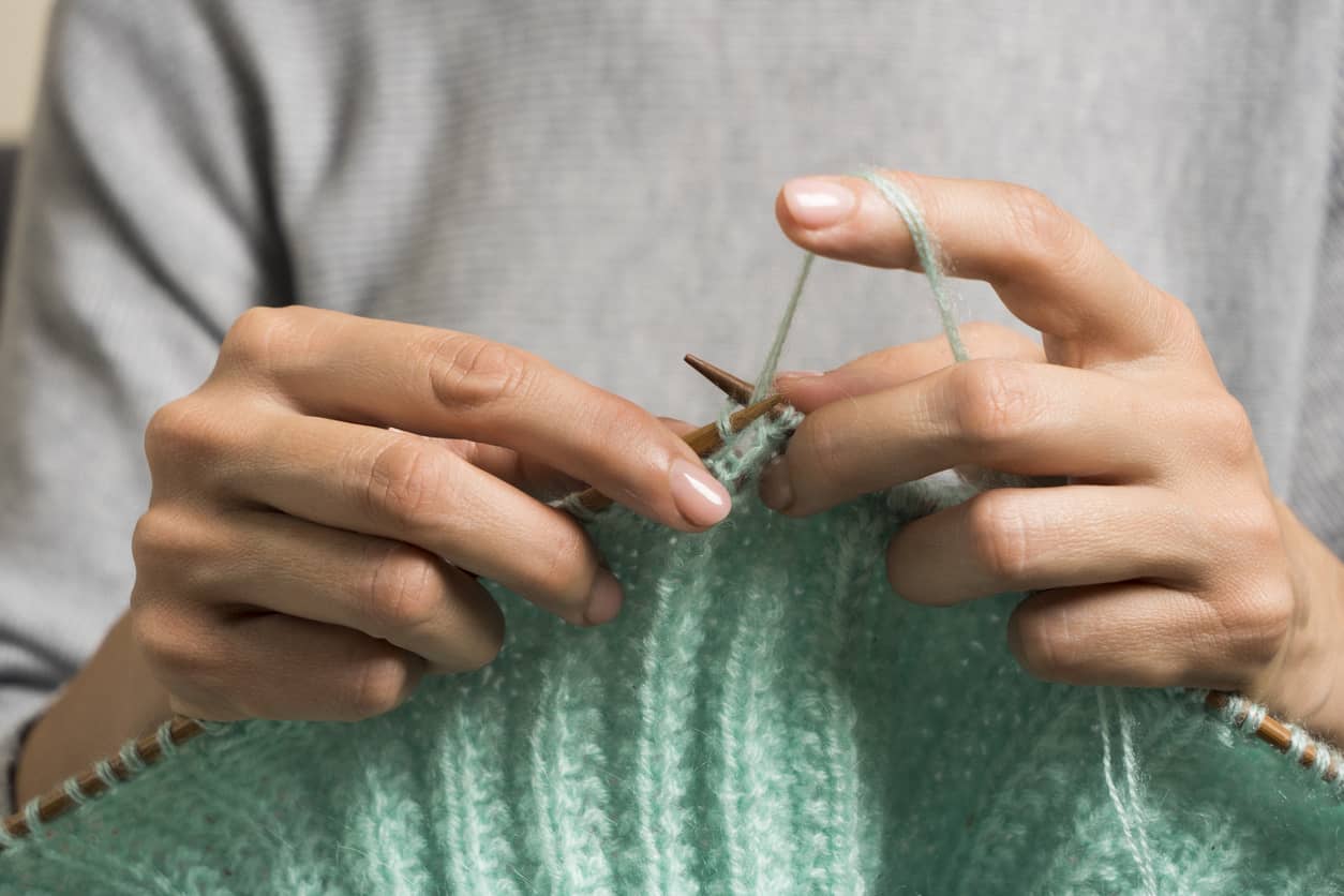 Woman's hands holding green knitting.