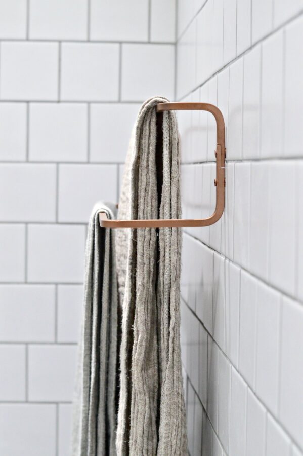 Copper spray painted bathroom towel rail, with towels hanging on it.