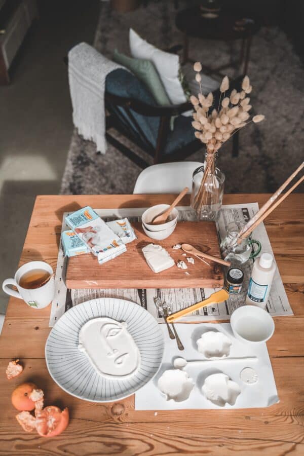 wooden table with lots of pieces of white pottery being created.